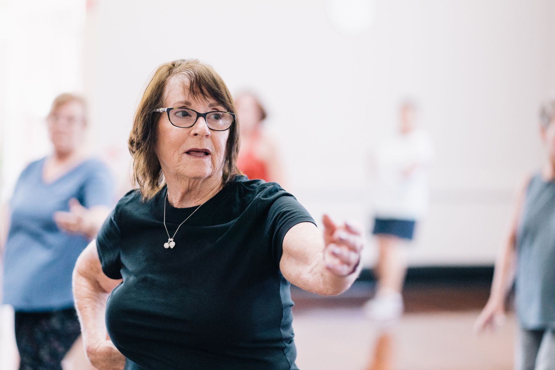 Mulher com mais de 60 anos em uma aula de dança, em movimento