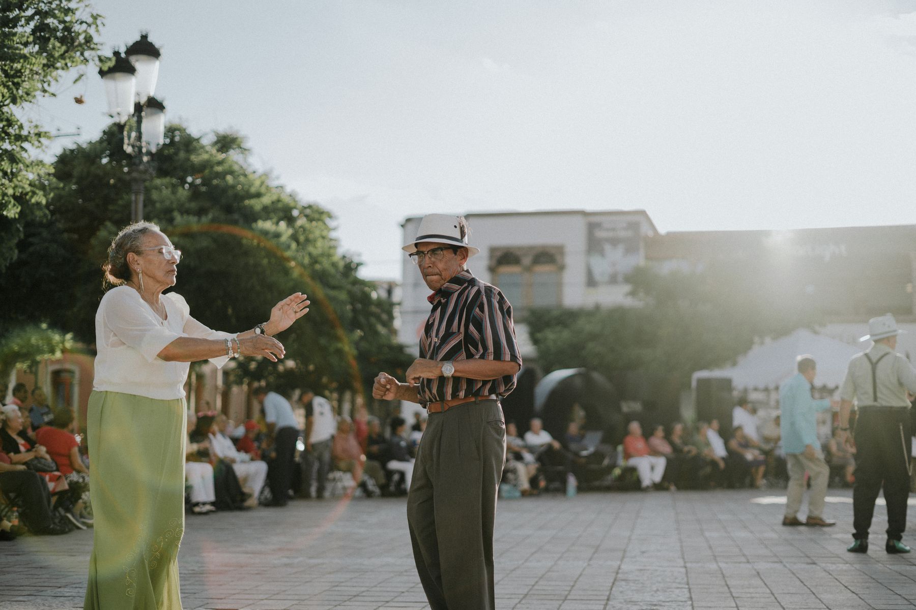 Casal de idosos dançando em uma praça ao ar livre